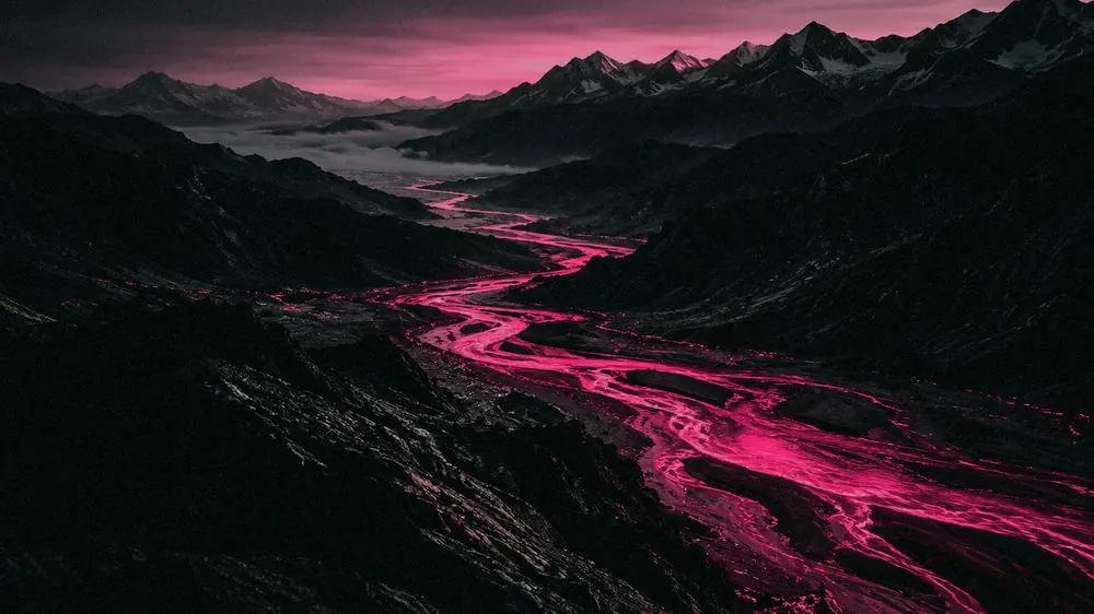 Vista aérea de um vale escuro onde vários braços de um rio se juntam num curso só, brilhando em magenta.